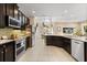 Modern kitchen with stainless steel appliances, dark cabinetry, and a seamless flow to the dining area at 1501 Prairie Oaks Dr, St Cloud, FL 34771