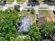 An aerial view of a single-story home with lush surrounding trees, a driveway, and a well-maintained lawn at 1906 S Summerlin Ave, Sanford, FL 32771