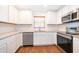 Modern kitchen featuring white cabinets, stainless steel appliances, granite countertops, and wood flooring at 2498 Iris Rd, Deland, FL 32724