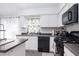 Kitchen with white cabinets, dark countertops, stainless steel appliances, and a window with colorful curtains at 254 Oak Park Pl, Casselberry, FL 32707