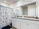 Well-lit bathroom with double vanity, a large mirror, and a shower-tub combo with a decorative curtain at 3354 Aruba Way, Haines City, FL 33844
