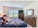 Bedroom with floral bedding, dark wood dressers, and a large window for ample natural light, offering comfort and style at 3354 Aruba Way, Haines City, FL 33844