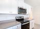 Modern kitchen featuring stainless steel microwave and range, with white cabinetry at 3354 Aruba Way, Haines City, FL 33844