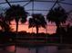 Serene sunset view from a screened-in pool area, casting vibrant colors across the sky and reflecting in the water at 3840 Caledonia Ave, Apopka, FL 32712