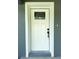 A close-up of a white front door with decorative glass, surrounded by a white frame and gray exterior at 4919 Nw 61St Ct, Ocala, FL 34482