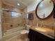 Bathroom featuring a bathtub with glass doors, granite countertop, and a decorative round mirror at 4981 Lake Cecile Dr, Kissimmee, FL 34746