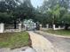Gated property entrance with a long driveway, mature trees, stone columns, and an iron gate at 4981 Lake Cecile Dr, Kissimmee, FL 34746