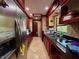 Galley kitchen with dark cherry wood cabinetry, granite counters, stainless steel appliances, and tile flooring at 4981 Lake Cecile Dr, Kissimmee, FL 34746