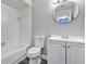 A well-lit bathroom features white fixtures, including a toilet, tub, and vanity with a circular mirror, offering a clean aesthetic at 5039 Jamaica # 10, Orlando, FL 32808