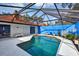 Screened pool features a geometric roof design, vibrant blue accent wall, and a white concrete patio, ideal for outdoor relaxation at 5039 Jamaica # 10, Orlando, FL 32808
