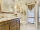 Bright full bathroom with decorative vanity, large mirror, custom window treatment, and tile floors at 5852 Medinah Way, Orlando, FL 32819