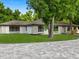 A one-story home with a well-manicured lawn, complemented by mature trees and stone accents at 625 N Central Ave, Oviedo, FL 32765