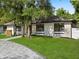 A one-story home with a well-manicured lawn, complemented by mature trees and stone accents at 625 N Central Ave, Oviedo, FL 32765