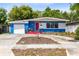 Inviting single-story home with a vibrant blue and white exterior, red door, and well-maintained front yard at 657 Overspin Dr, Winter Park, FL 32789