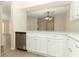 Bright kitchen featuring white cabinets, stainless steel dishwasher, and light wood-look flooring at 662 Kenwick Cir # 102, Casselberry, FL 32707