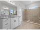 Bright bathroom featuring a walk-in shower with tile surround and a double vanity with granite countertop at 6875 Bridgman St, Orlando, FL 32827
