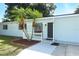 Welcoming front entrance of a light blue home with a dark door, palm trees, and gray walkway leading to the entrance at 707 N Solandra Dr, Orlando, FL 32807