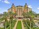 Resort exterior shows manicured walkway leading to the building entrance with palm trees, gardens, and porte cochere at 7593 Gathering Dr # 502, Reunion, FL 34747