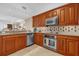 Modern kitchen with stainless steel appliances, wooden cabinetry, and a view to the dining and living areas at 7593 Gathering Dr # 502, Reunion, FL 34747