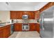 Well-equipped kitchen featuring stainless steel appliances, wooden cabinetry, and tile backsplash at 7593 Gathering Dr # 502, Reunion, FL 34747