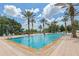Large rectangular swimming pool surrounded by palm trees and lounge chairs on a sunny day at 7593 Gathering Dr # 502, Reunion, FL 34747