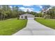 Well-maintained home featuring a long driveway, two-car garage and green lawn at 8202 Sw 123Rd Ter, Dunnellon, FL 34432