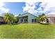 Spacious backyard with well-maintained lawn, tropical trees, and covered patio at 9563 Myrtle Creek Ln, Orlando, FL 32832