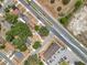 Aerial view showcasing the property, road, adjacent buildings, and surrounding residential area with lush trees at 1000 E Dixie Ave, Leesburg, FL 34748