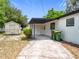 Backyard featuring a carport, an exterior storage unit, trashcans, and a green shrub at 1000 E Dixie Ave, Leesburg, FL 34748