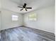 Spacious bedroom with gray wood-look flooring features a ceiling fan and a sunlit window view at 1000 E Dixie Ave, Leesburg, FL 34748