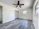 Bedroom featuring gray wood-look flooring with a ceiling fan, closet, and sunlit window at 1000 E Dixie Ave, Leesburg, FL 34748