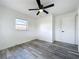 Bright bedroom with ceiling fan features gray wood-look flooring and a sunlit window at 1000 E Dixie Ave, Leesburg, FL 34748