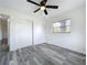 Bedroom with gray wood-look floors has a ceiling fan, closet and a sunny window view at 1000 E Dixie Ave, Leesburg, FL 34748