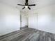 Bright bedroom with gray wood-look flooring has a ceiling fan and access to another room at 1000 E Dixie Ave, Leesburg, FL 34748