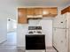 Close-up of the kitchen featuring cabinets, stove, refrigerator and wood-look vinyl flooring at 1000 E Dixie Ave, Leesburg, FL 34748