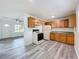 Bright kitchen featuring wood cabinets, white appliances, and wood-look vinyl flooring at 1000 E Dixie Ave, Leesburg, FL 34748