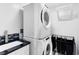 Modern laundry room with a stacked washer and dryer, utility sink, and a dark countertop at 1014 Seminole Creek Dr, Oviedo, FL 32765