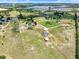 Aerial view showcases a large rural property with a home, barn, and swimming pool amidst green pastures at 11115 Romance Ct, Winter Garden, FL 34787