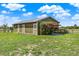 View of barn with metal roof and six doors in a green pasture with bougainvillea at 11115 Romance Ct, Winter Garden, FL 34787