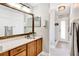 Bathroom featuring wood cabinets, a large mirror, and walk-in shower, accented with a modern ceiling light at 11115 Romance Ct, Winter Garden, FL 34787