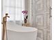 Freestanding tub with bronze fixtures and a decorative sliding shower door in a naturally lit bathroom at 11115 Romance Ct, Winter Garden, FL 34787