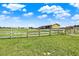 Expansive green land with wooden fence and outbuildings under a bright sky at 11115 Romance Ct, Winter Garden, FL 34787