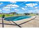Beautiful in-ground pool with a screened enclosure, surrounded by lush greenery and blue skies at 11115 Romance Ct, Winter Garden, FL 34787