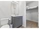 Well-lit bathroom with a gray vanity, toilet, and a walk-in closet with shelving at 15358 Arcadia Bluff Loop, Winter Garden, FL 34787
