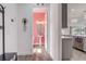 Hallway view to a charming half bath featuring pink walls and stylish fixtures and a pendant light in the kitchen at 15378 Gilligan Ct, Winter Garden, FL 34787