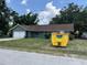 Charming single-story home with an attached garage, yard, and large garbage dumpster at 1675 Louis Dr, Kissimmee, FL 34758