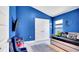 This bedroom is painted a vibrant blue with a bed and gaming-themed decor at 228 Bergamot Loop, Davenport, FL 33837