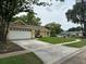View of the yellow single-Gathering home showcasing the well-maintained lawn and extended driveway at 243 Country Landing Blvd, Apopka, FL 32703