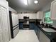 Bright kitchen with white and blue cabinets, black countertop, and stainless steel appliances at 243 Country Landing Blvd, Apopka, FL 32703