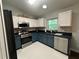 Well-lit kitchen features stainless steel appliances, bright white tile floors, and white and blue cabinets at 243 Country Landing Blvd, Apopka, FL 32703